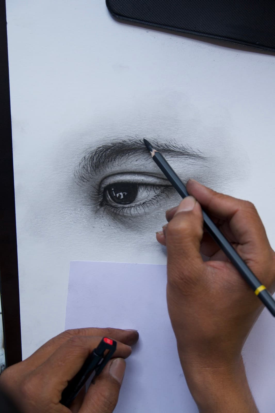 Close-up of an artist refining a realistic charcoal eye drawing