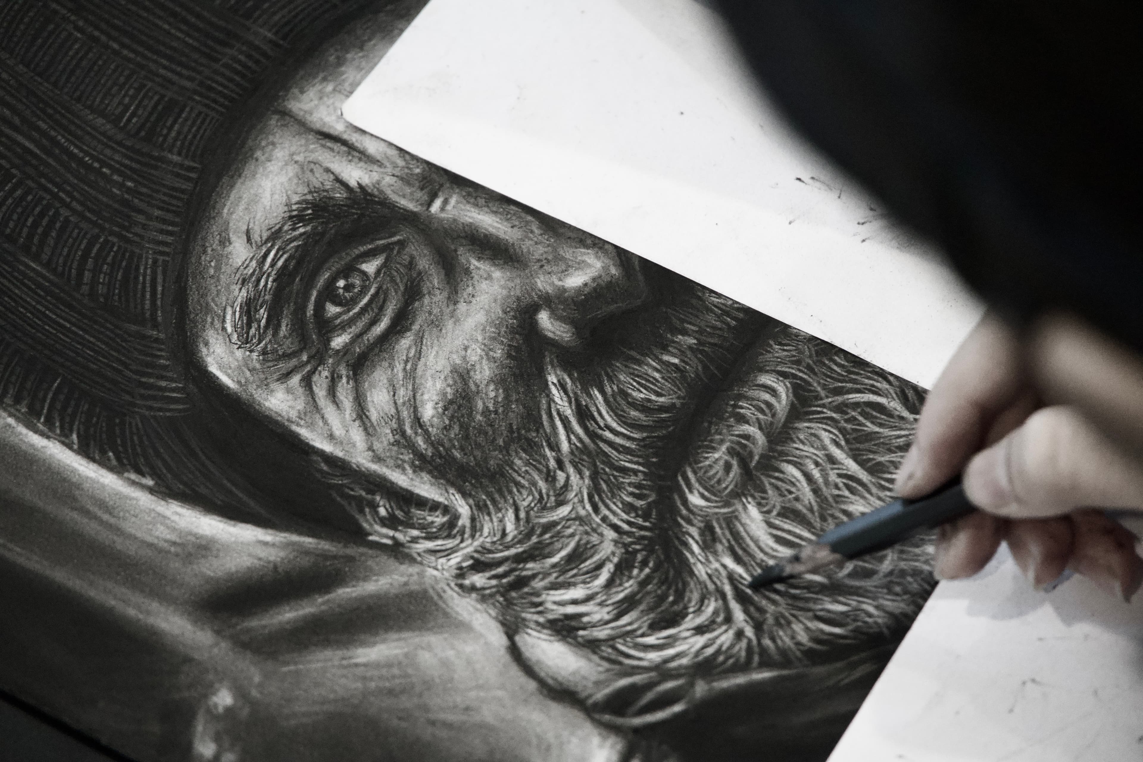 Artist refining a detailed charcoal portrait drawing