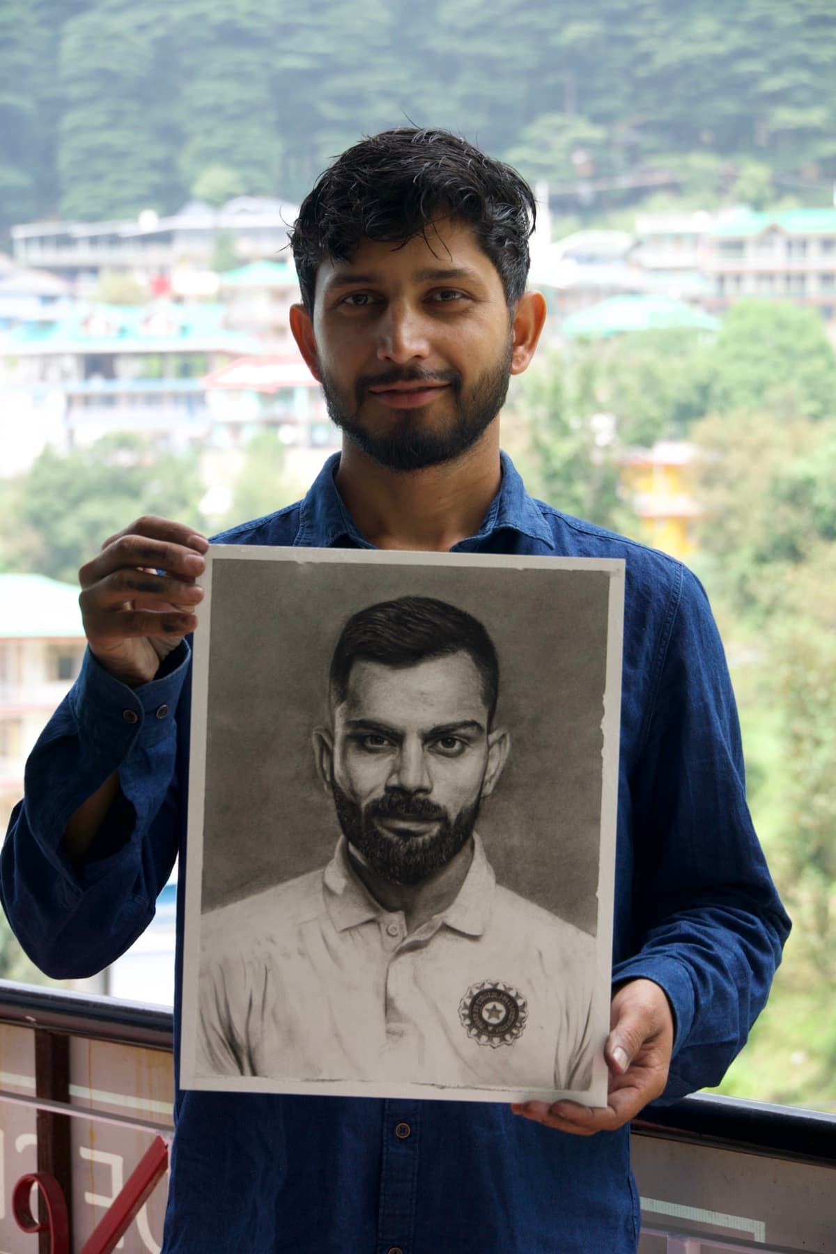Student holding a completed charcoal portrait outdoors
