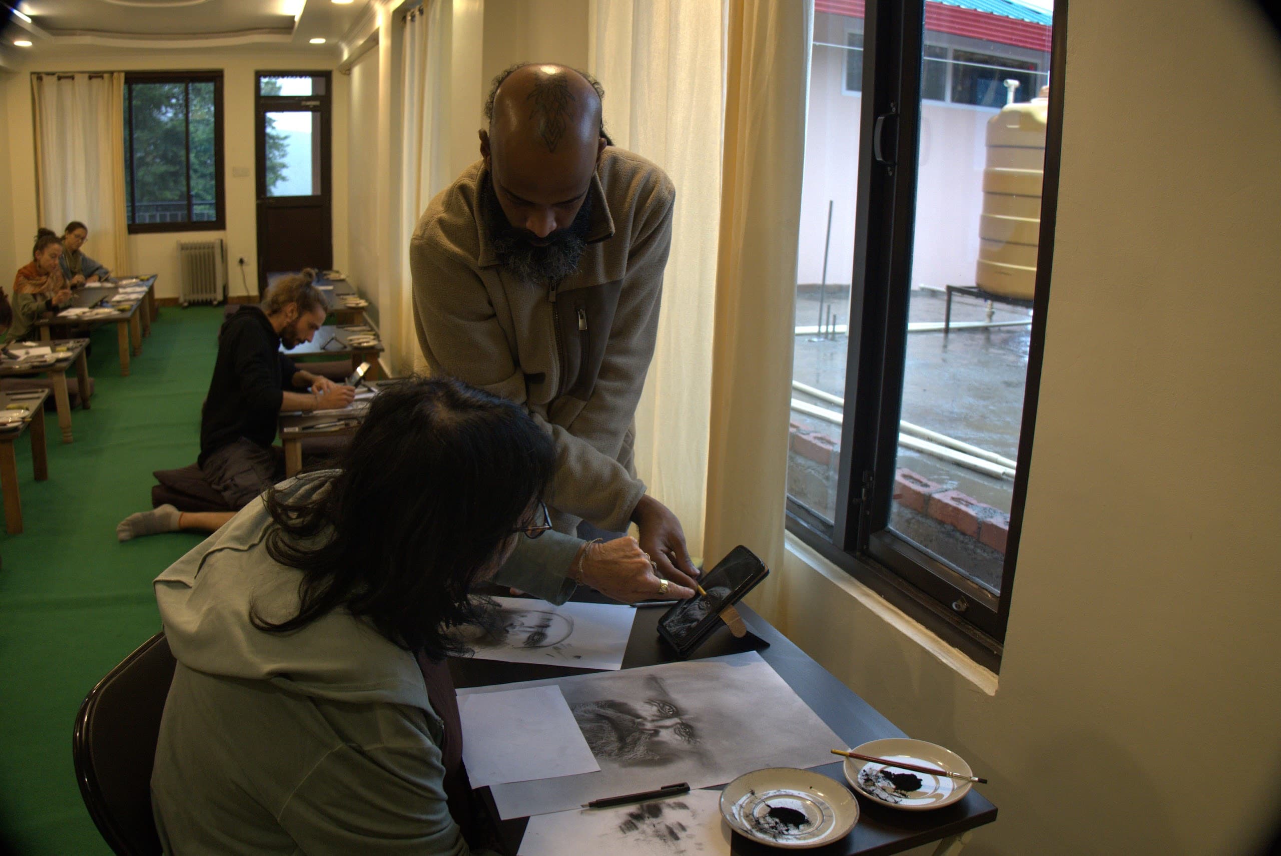 Teacher guiding a student through a charcoal portrait exercise