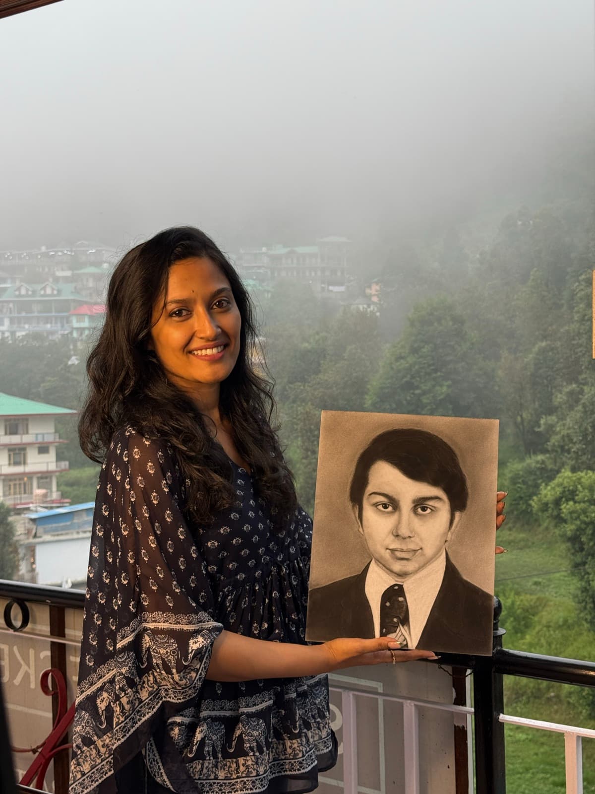 Student holding a finished charcoal portrait in Dharamkot