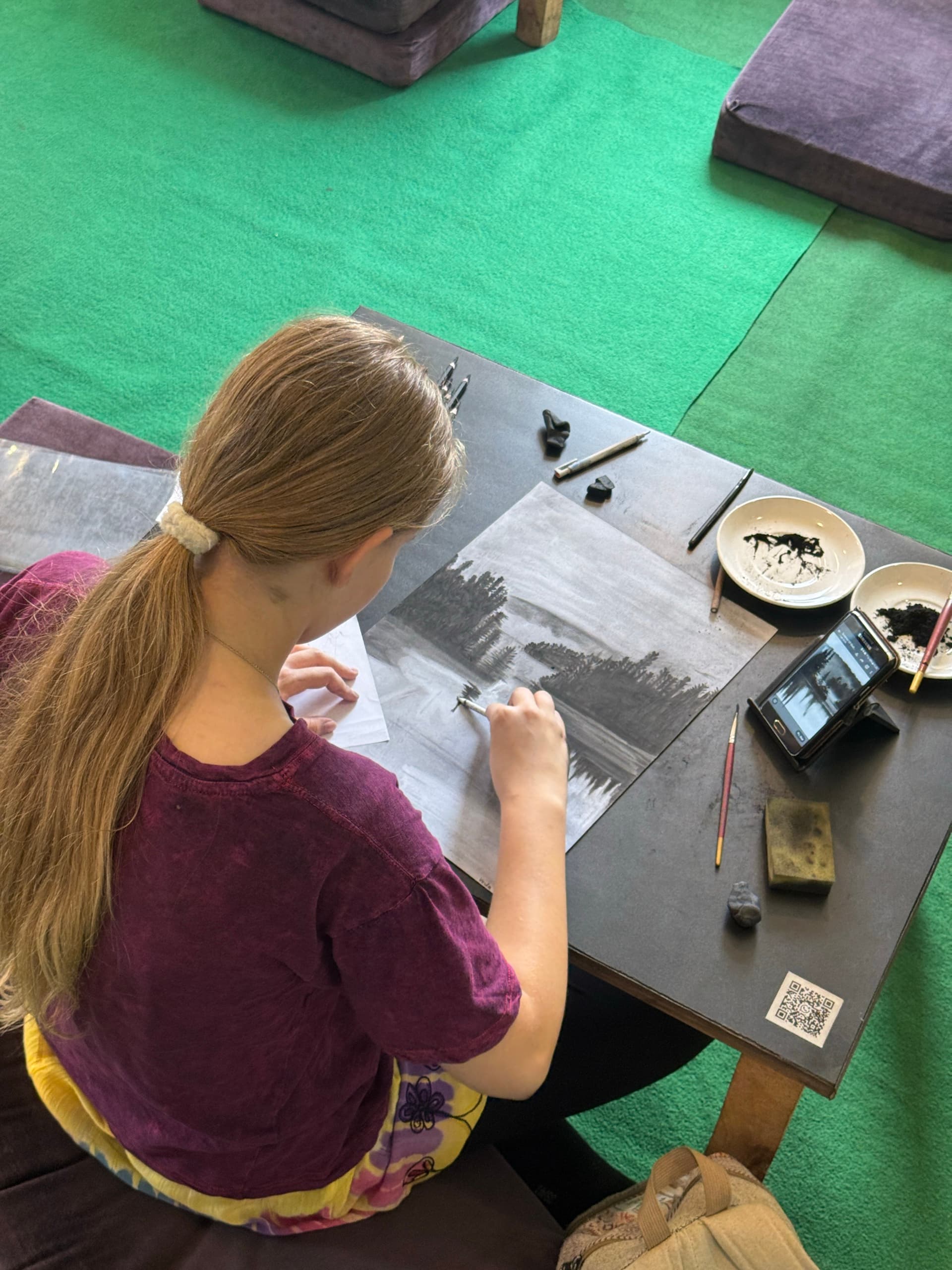 Student refining a charcoal landscape study during the Objects Course