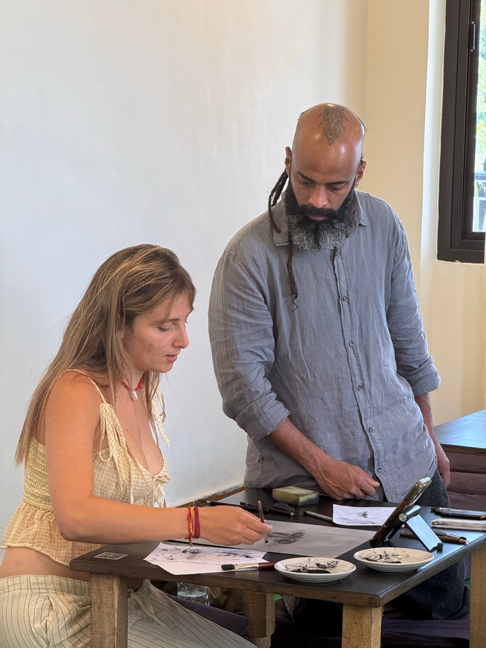 Teacher guiding a student through a charcoal drawing exercise